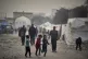 Displaced Palestinians walk by tents at the Islamic Universi