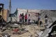 Palestinians inspect the remains of a displacement tent hit 
