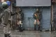 Indian paramilitary soldiers take shelter near closed shops 