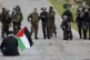 A Palestinian demonstrator holds a national flags in front o