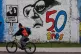 A man pedals his bicycle past a mural marking the 50th anniv