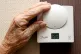 An elderly lady adjusting her thermostat on at home in Liver