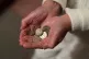 An elderly woman holding pound coins in her hands, in Poole,