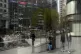 Pedestrians and office buildings are reflected on a brokerag