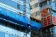 Workmen remove the cladding from the facade of a block of fl