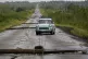 People drive along a road littered with fallen power lines a