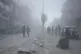 Palestinians walk through dust by the rubble of houses, dest