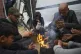 Members of the Abed family warm up by a fire at a tent camp 