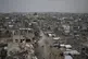 Palestinians walk surrounded by the rubble of destroyed home