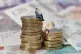 Models of a man and woman stand on a pile of coins and bank 