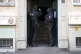 Police officers stand in a building entrance during a raid a
