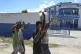 People raise their arms while walking past a police station 