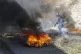 A police officer works to clear barricades of burning tires 