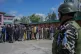An Indian paramilitary soldier guards as people stand in que