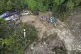 Rescuers use heavy machines to clear mud from a road followi