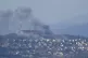 Fires and black smoke rise from between the houses of the no