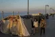 People walk past tents set up as temporary shelters by displ