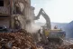 Rescue workers use excavators to remove the rubble of a dest