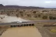 A car drives through a bridge as flood water caused by heavy