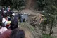People watch earthmovers removing automobile debris and the 