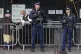 Armed police officers guard the entrance as family and survi