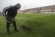 A groundskeeper brushes the grass before a Scottish Premiers