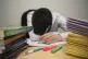 A primary school teacher looking stressed next to piles of c