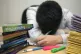 A primary school teacher looking stressed next to piles of c