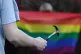 A person holding a hammer behind someone wearing an LGBT pri