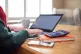 A woman using a laptop on a dining room table set up as a re