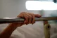 The hand of a patient grips the rail of a hospital bed in th