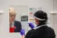 Prime Minister Boris Johnson looks at a swab being held by a