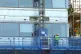 Workmen remove the cladding from the facade of a block of fl