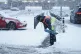 A member of staff from Tesco Extra shovels snow outside the 