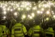 People in the crowd turn on their phone torches in Clapham C