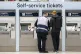 A member of staff assists a person at the ticket machines in