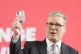 Sir Keir Starmer holds a Labour pledge card while speaking a