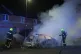 Firefighters tend to a burning police car burns as officers 