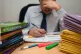 A school teacher looking stressed next to piles of classroom