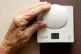 An elderly lady adjusting her thermostat on at home in Liver
