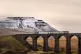 A train crosses over the Ribblehead Viaduct with the snow ca