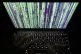 A user on a laptop displaying a ‘Matrix’-style screensav