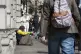 Members of the public walking past a homeless man begging in