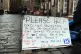 A sign near a homeless person and their dog on the Royal Mil
