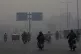 Motorcyclists drive on a highway as smog envelops the areas 