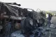 
People look at a burnt vehicle which was torched by gunmen 