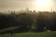 A woman walks a dog during sunrise on Primrose Hill, London,