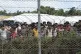 Rohingya refugees gather near a fence during a government or