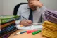 A school teacher looking stressed next to piles of classroom