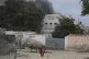 A woman walks on the beach as black smoke is seen rising in 